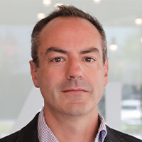 Headshot of Adam Scraba wearing a white collared dress shirt and blazer smiling