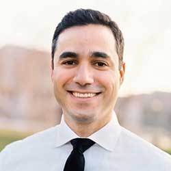Headshot of Mostafa Toloui wearing a white button up shirt and black tie smiling